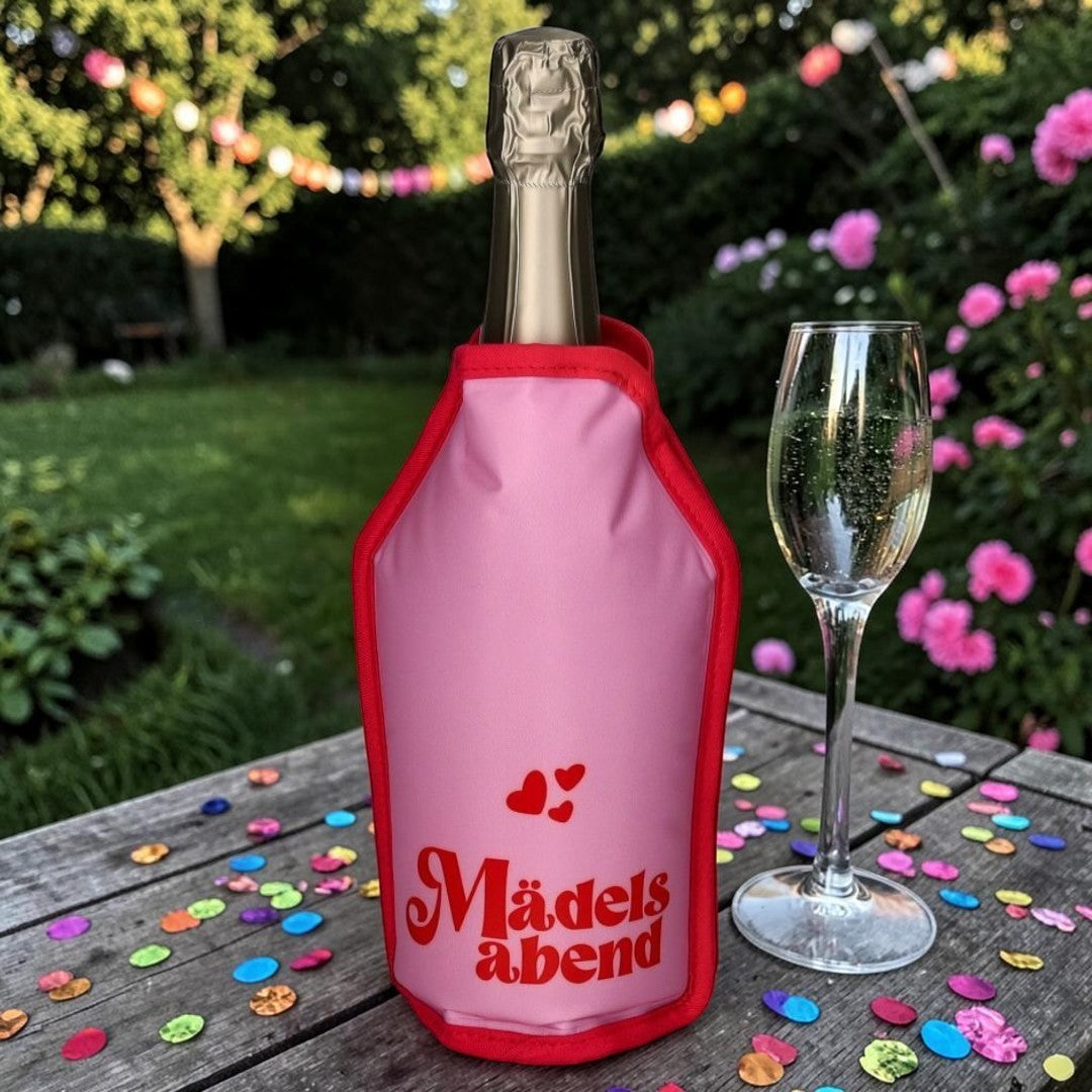 Nomafu Froid Kühlmanschette in Pink mit Mädelsabend-Schriftzug um eine Weinflasche auf einem Gartentisch