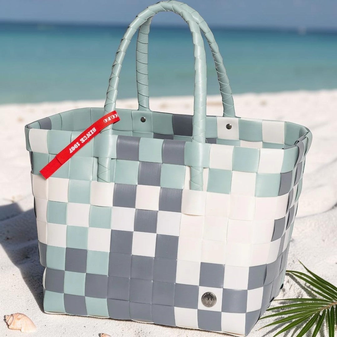 Nomafu ICE-BAG Shopper aus geflochtenem Recycling-Kunststoff in Pastellfarben am Strand mit rotem Markenband