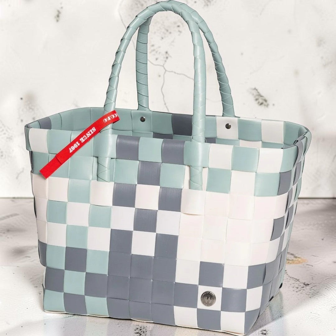 Nomafu ICE-BAG Klassik Shopper aus geflochtenem, mehrfarbigem Kunststoff in Blau, Grau und Weiß mit rotem Markenband.