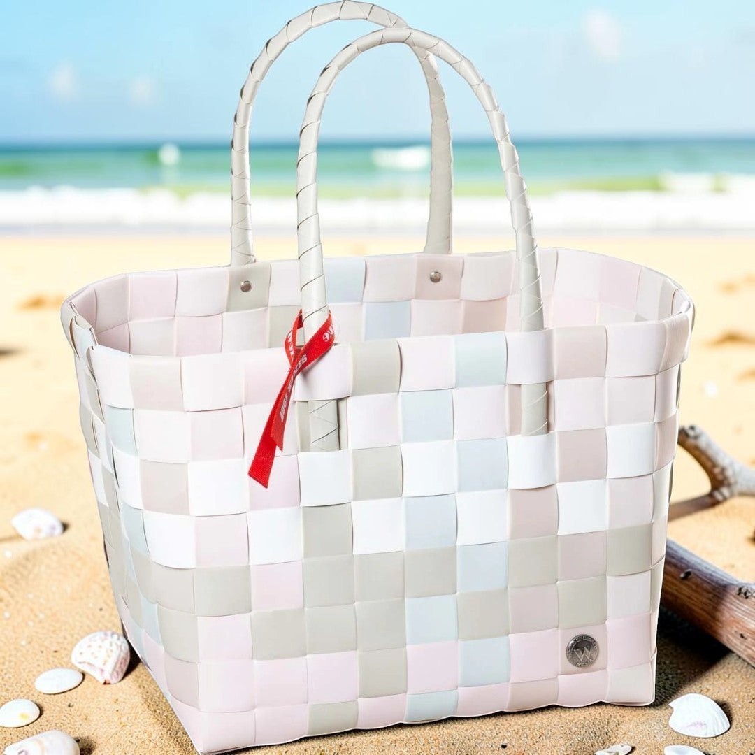Nomafu ICE-BAG Shopper in Pastellfarben aus geflochtenem Recycling-Kunststoff mit rotem Markenband am Strand