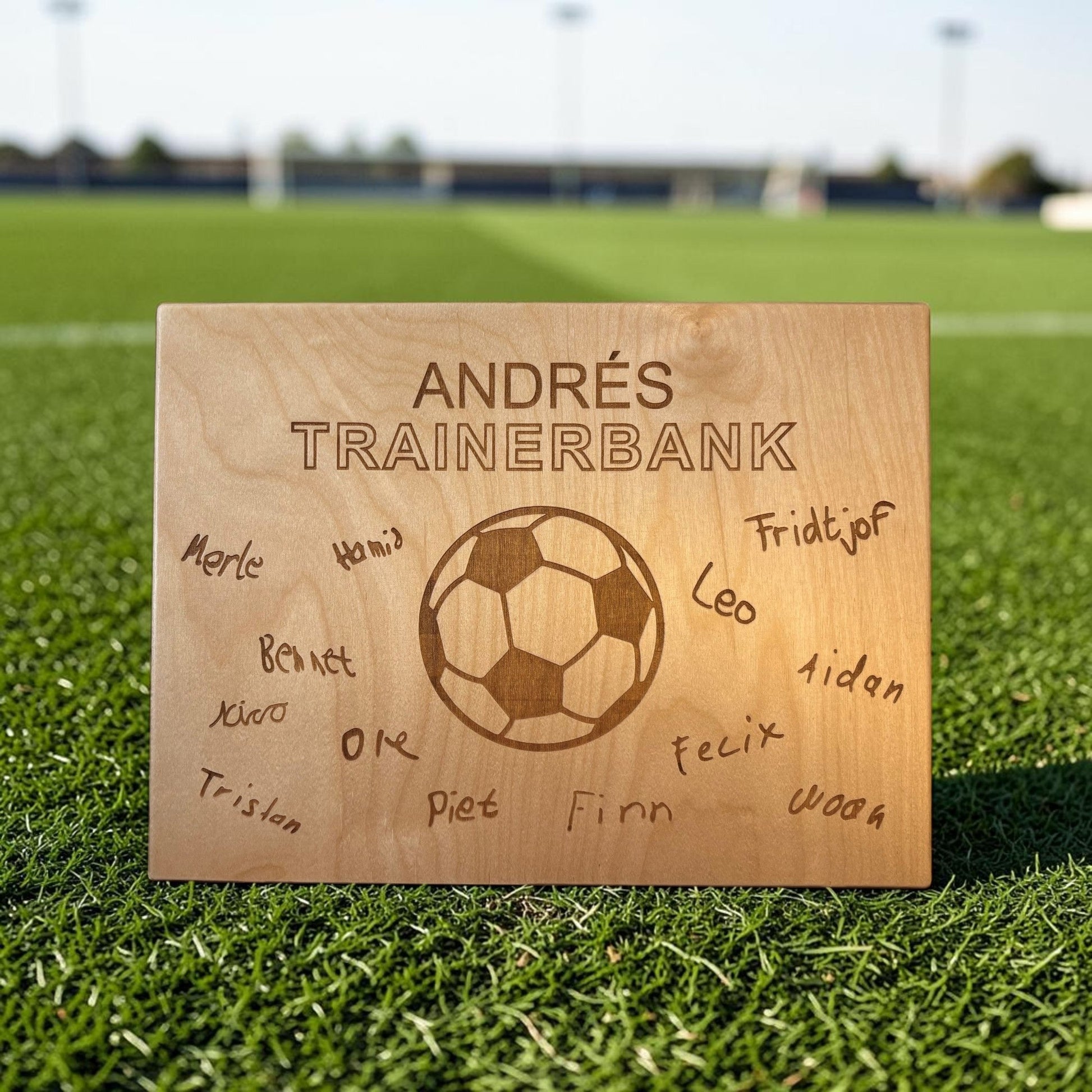 Nomafu wooden crate seat topper with custom laser-engraved soccer ball and team names on a green grass field
